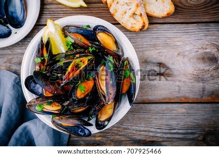 Delicious seafood mussels with with sauce and parsley.  Lemon and baguette . Clams in the shells.  Top view. 