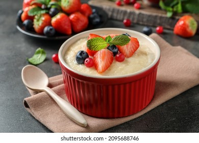 Delicious semolina pudding with berries and mint served on grey table
