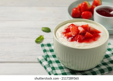 Delicious semolina pudding with strawberries and jam on white wooden table, space for text