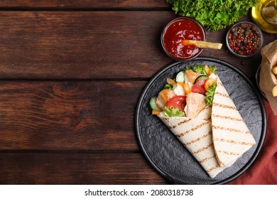 Delicious shawarma with chicken meat and vegetables  served on wooden table, flat lay. Space for text