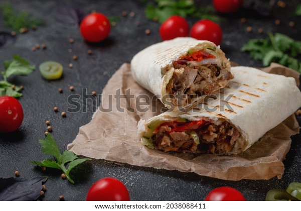 Delicious shawarma and lavash tacos on a\
dark stone table. Fast food restaurant. Healthy option of fast\
food. Tasty fresh wrap sandwiches with beef meat and vegetables,\
Traditional Middle Eastern\
snac