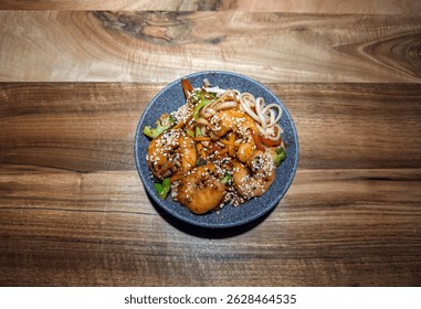 Delicious Shrimp Udon Noodle Stir-fry with Vegetables and Sesame Seeds in a Bowl.Asian Teriyaki Shrimp and Udon Noodles Bowl, Top View on Rustic Wooden Table.