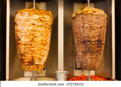 Delicious slabs of skewered fast food shawerma chicken and lamb meat turn side by side on a spit. This is part of a common sandwich found in the Middle East.