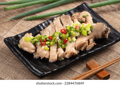 Delicious sliced chicken with scallion oil sauce on wooden table, close up.