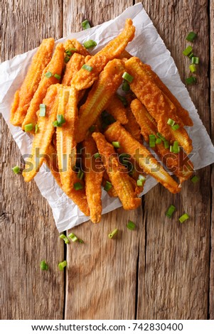 Delicious snack of fried baby corn close-up on the table. Vertical top view from above
