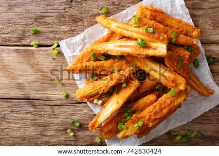 Delicious snack of fried baby corn close-up on the table. horizontal top view from above
