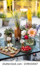 Delicious Snack On Garden Table Decorated With Different Flowers At Backyard