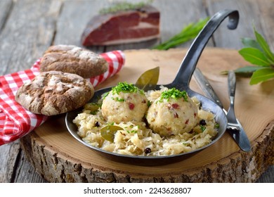 Delicious South Tyrolean bacon dumplings served on sauerkraut in an iron frying pan