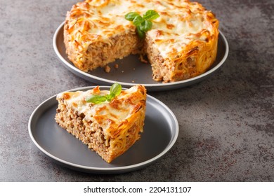 Delicious spaghetti pasta pie with ground beef, tomato sauce and parmesan cheese and mozzarella close-up in a plate on the table. horizontal