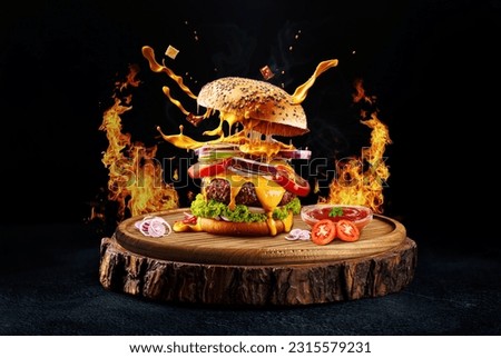 Delicious spicy burger ads with burning fire on dark background. Fresh tasty burger on old wooden base