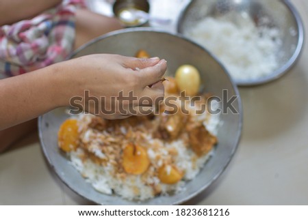 Delicious spicy homemade chicken biryani making in bowl by an indian woman. it's a popular Indian and Pakistani food. selective focus on the hand.