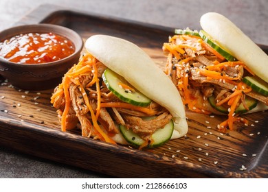 Delicious steamed bao buns sandwiches with pulled pork close-up on a wooden tray on the table. horizontal