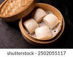 Delicious steamed bao buns in a traditional bamboo steamer basket.  Asian cuisine, Chinese food, dim sum, snack, appetizer.