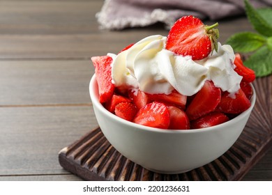 Delicious strawberries with whipped cream served on wooden table, closeup - Powered by Shutterstock