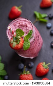 Delicious strawberry, mulberry and blueberry smoothie garnished with fresh berries and mint in glass. soft focus. beautiful appetizer pink raspberries, well being and weight loss concept.