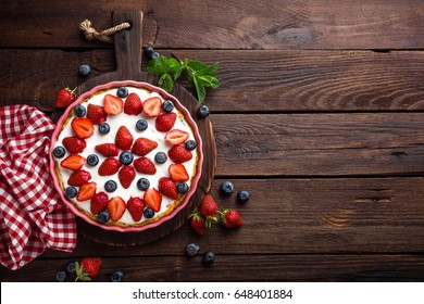 Delicious strawberry pie with fresh blueberry and whipped cream on wooden rustic table, cheesecake, top view - Powered by Shutterstock