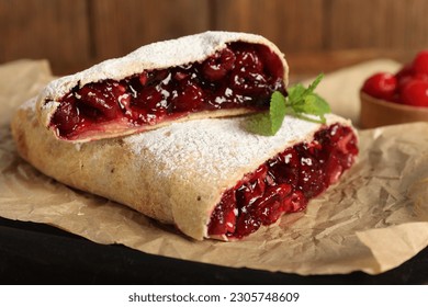 Delicious strudel with cherries on parchment, closeup