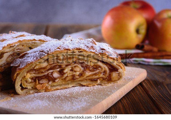 Delicious strudel stuffed with apples and\
cinnamon and red apples on\
background