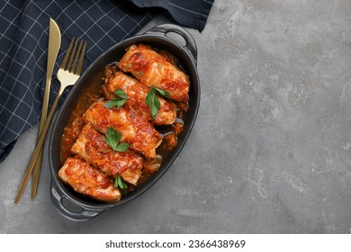 Delicious stuffed cabbage rolls cooked with tomato sauce on grey table, flat lay. Space for text