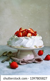 Delicious summer cake "Pavlova" with whipped cream and fresh strawberry on a light slate, stone or concrete background.