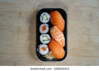 Delicious Sushi In A Black Plastic Box On A Bamboo Wood Board.