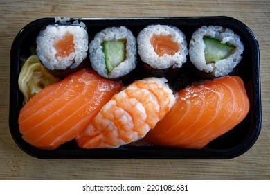 Delicious Sushi In A Black Plastic Box On A Bamboo Wood Board.