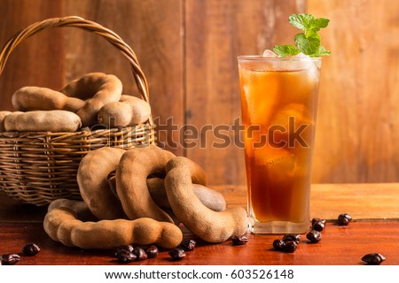 Delicious sweet drink tamarind juice and ice with mint leaves on rustic wooden table. Selective focus and toned image. Copy space.