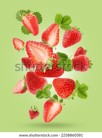 Delicious sweet strawberries and leaves falling on light green background
