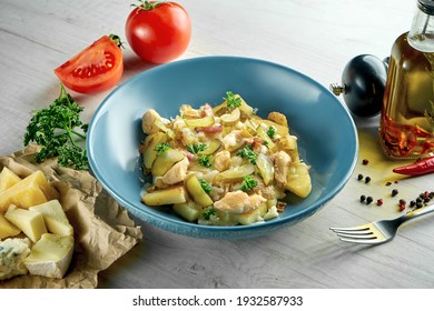 Delicious Swiss Dish - Raclette With Cheese, Bacon, Chicken, Potatoes And Mushrooms, Served In A Blue Bowl On A Wooden Background. Restaurant Food