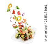 Delicious tacos. Ingredients falling into tortillas on white background