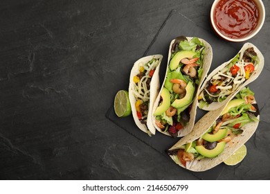 Delicious tacos, lime and sauce on black table, flat lay. Space for text - Shutterstock ID 2146506799