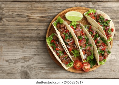 Delicious tacos with meat, vegetables and lime on wooden table, top view. Space for text - Powered by Shutterstock