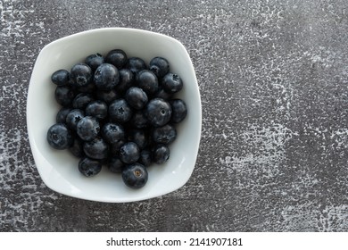 Delicious, tasty blueberries on a rustic background. Still life food photography. Blank space left around the berries for your text.