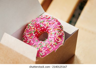 Delicious Tasty Sweet Glazed Pink Donut In Paper Box Close-up. Sale, Purchase, Delivery Of Fresh Baked Goods