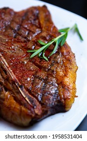 Delicious T-bone Beef Steak Cooked On Grill And Served On White Plate With Rosemary Herb In Restaurant.Download Royalty Free Curated Images Collection With Gourmet Foods For Design Template