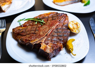 Delicious T-bone Steak Cooked On Grill For Dinner.Gourmet Beefsteak Served For Dinner On White Plate In American Meat Restaurant.Download Royalty Free Curated Images Collection With Foods For Design