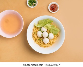 Delicious Thai Food Fishball Noodle In A Bowl With Soup, Chili Sauce And Spring Onion Top View On Wooden Table