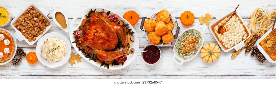Delicious Thanksgiving turkey dinner. Top view table scene on a rustic white wood banner background. Turkey, mashed potatoes, stuffing, pumpkin pie and sides.