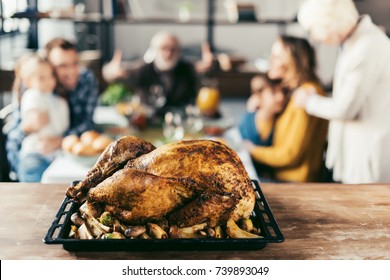 Delicious Thanksgiving Turkey On Table With Blurred Family On Background