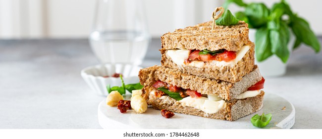 Delicious toast with white asparagus, tomatoes, mozzarella, sun-dried tomatoes and basil on white marble board. Healthy food concept with copy space.