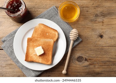 Delicious toasted bread slices with butter served on wooden table, flat lay