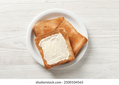 Delicious toasted bread slices with butter on white wooden table, top view