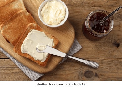 Delicious toasted bread slices with butter served on wooden table, flat lay