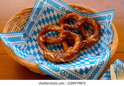 Delicious traditional Bavarian Brezeln or pretzels with a brown salty crust on a traditional Bavarian cocktail napkin in a basket                                - Shutterstock ID 2189979875