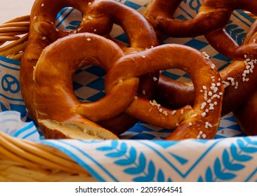Delicious traditional Bavarian Brezeln or pretzels with a brown salty crust on a traditional Bavarian cocktail napkin in a basket at the Bavarian Oktoberfest (Munich, Bavaria, Germany)                 - Shutterstock ID 2205964541