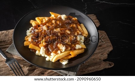 Delicious traditional canadian dish poutine gravy and fries with cheese curd in dark environment