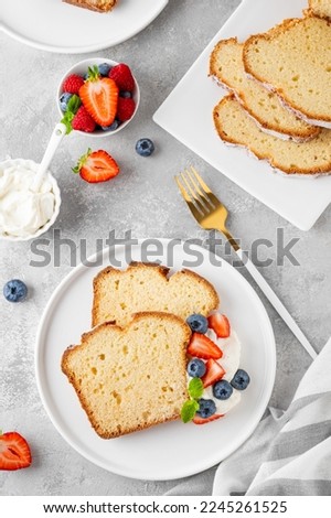 Delicious vanilla pound cake served with fresh berries and whipped cream on a gray concrete background. Selective focus, copy space Stock photo © 