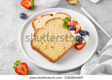 Delicious vanilla pound cake served with fresh berries and whipped cream on a gray concrete background. Selective focus, copy space
