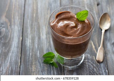 Delicious vegan chocolate mousse with banana, cocoa and mint in glass on a wooden surface, selective focus, copy space - Shutterstock ID 678359128