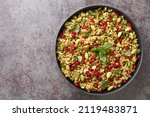 Delicious vegetarian freekeh with pomegranate, nuts and herbs close-up in a plate on the table. horizontal top view from above
